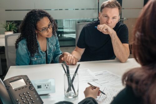 Couple sitting at table with documents holding hands