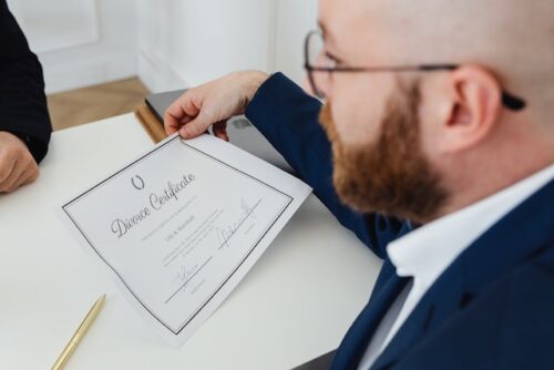 man with glasses holding divorce certificate