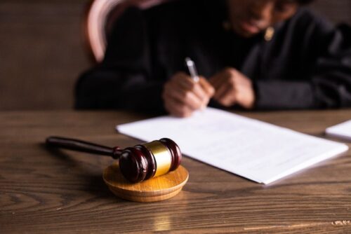 judge signing paper with gavel on desk