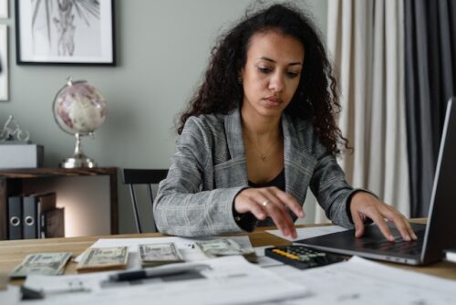 woman with money, documents, and computer at desk