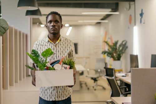 man holding box of personal belongings in office