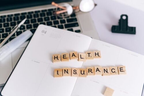 Scrabble letters "health insurance" near computer