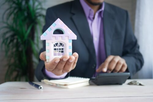 man in suit using calculator holding small home